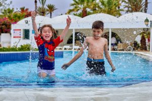 imagen de dos niños en la piscina salpicando agua después de hacer natación en SABS