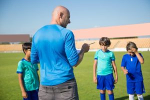 imagen de un grupo de niños que pertenecen a un club deportivo de fútbol hablando con su entrenador en las instalaciones deportivas de SABS